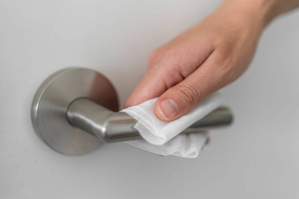 photo : Coronavirus COVID-19 Prevention cleaning woman wiping doorknob with antibacterial disinfecting wipe for killing corona virus on touching surfaces or touching public bathroom handle with tissue.