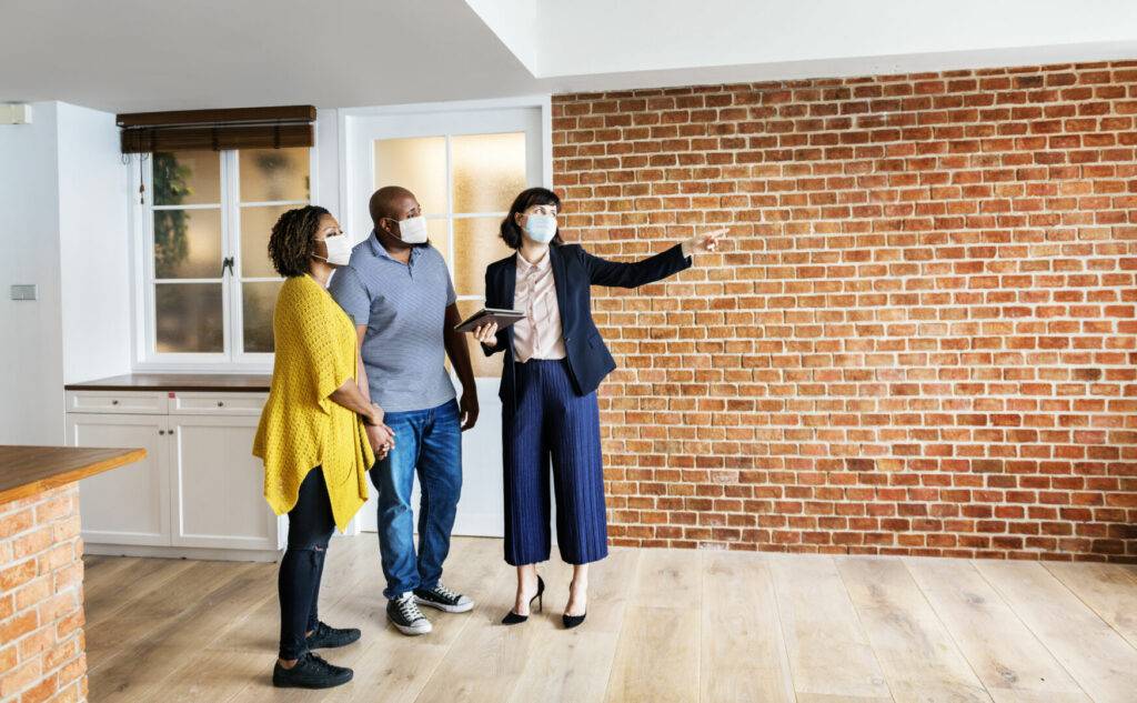photo : Real estate agent and customer in face mask looking at a new project