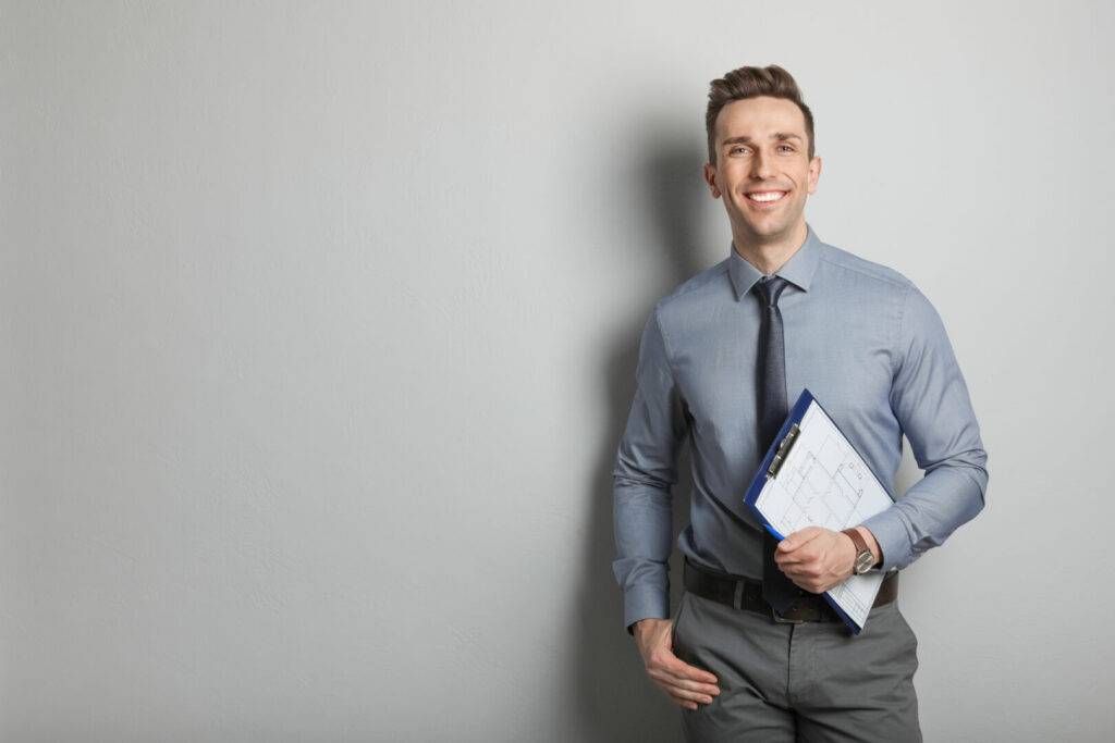 photo : Male real estate agent with clipboard on grey background