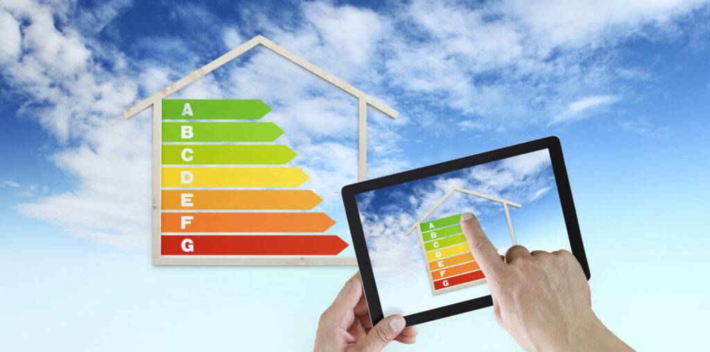 photo : hand touch screen of digital tablet with house shape and energy efficiency chart symbol, isolated on blu sky background, green buildings and save energy eco sustainability