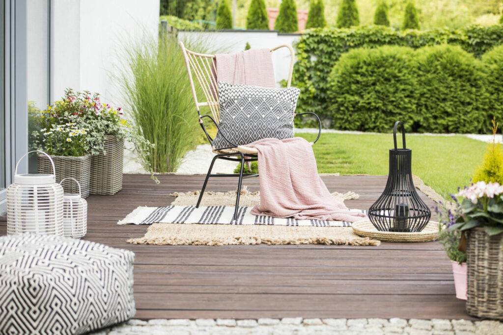 photo : Real photo of a white pillow and pink blanket on a rattan chair standing in the garden of a luxurious house