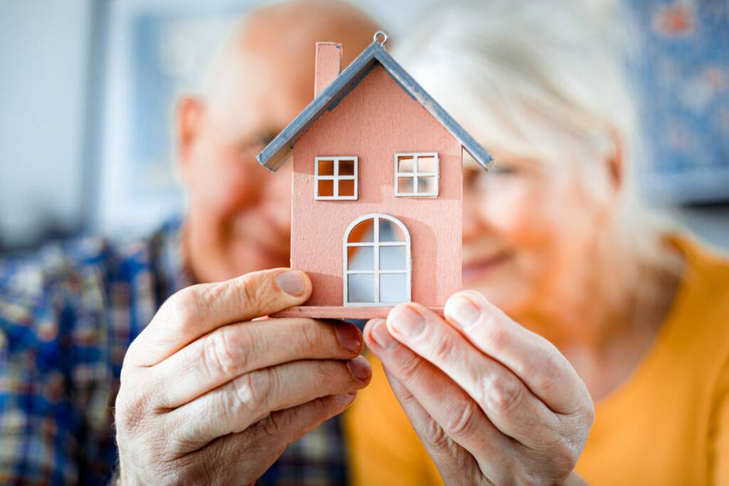 photo : New house concept, happy senior couple holding small home model