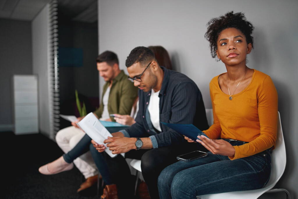 photo : Unemployed young african american woman feeling stressed about tedious waiting sitting in queue with other candidates for job interview