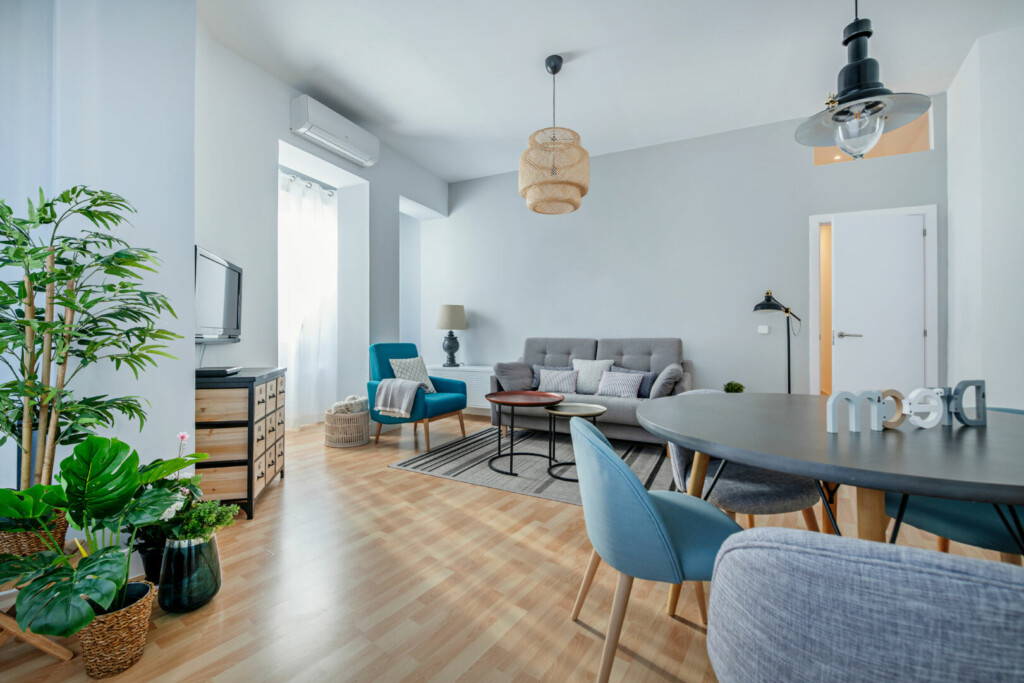 photo : Photo of a living room with a dining table in a vacation rental apartment decorated with soft tones, contemporary furnishings and natural plants.