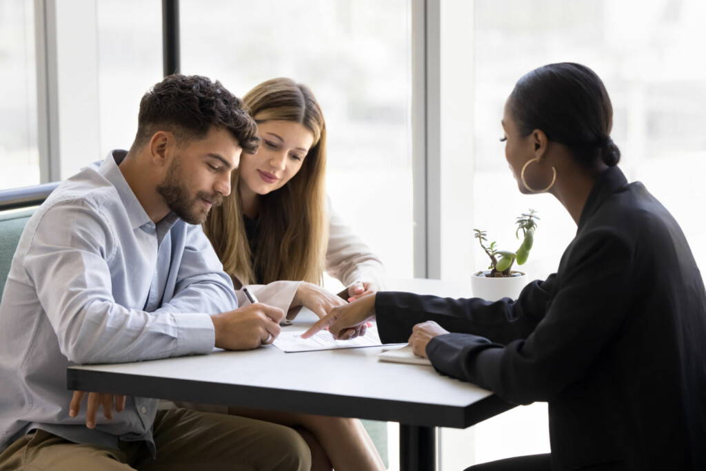 photo : Confident young African realtor pointing at paper agreement for customers