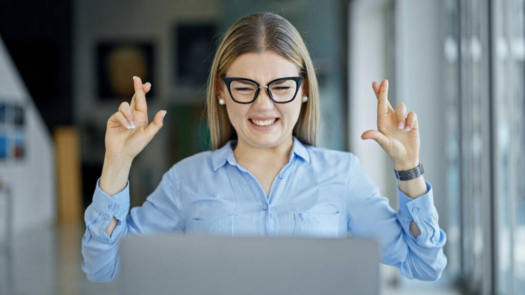 photo : Young blonde woman business worker using laptop crossing finger for lucky at office