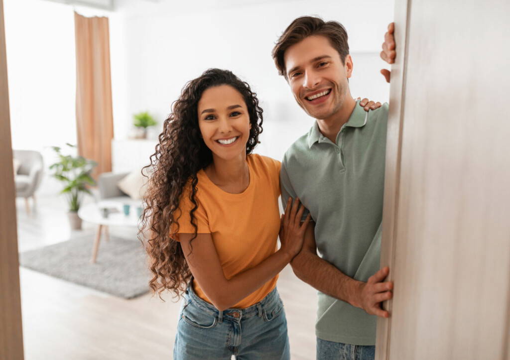 photo : Happy young couple inviting people to enter home