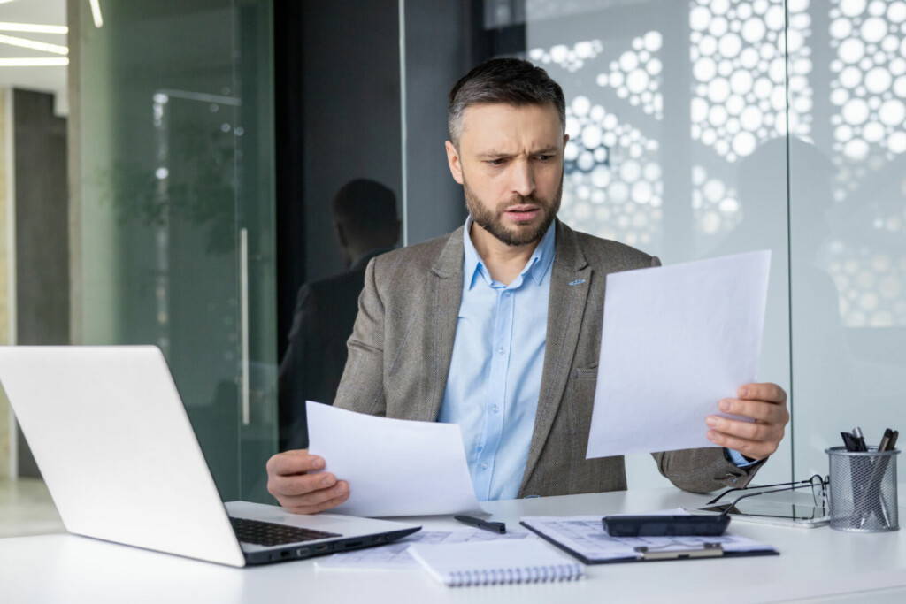 photo : Businessman reviewing documents with concern in modern office