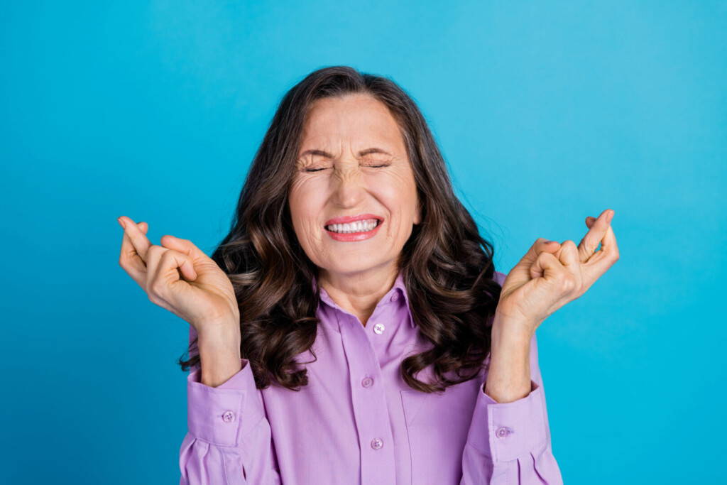 photo : Photo of uncertainn nervous woman wear violet shirt fingers crossed empty space isolated blue color background