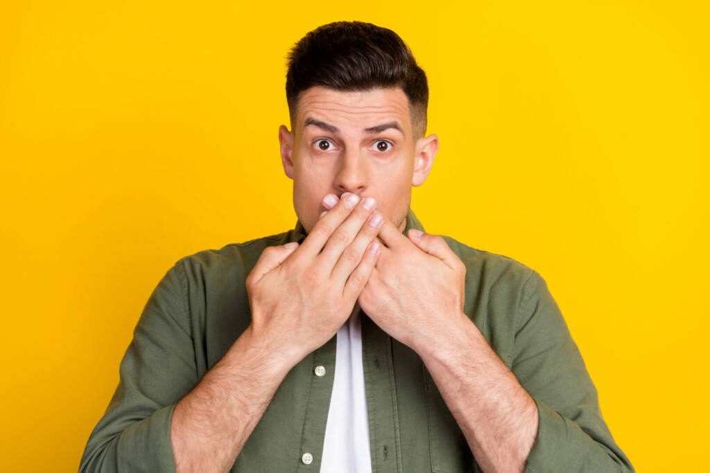 photo : Photo portrait man covered mouth with hands keeping secret isolated vibrant yellow color background