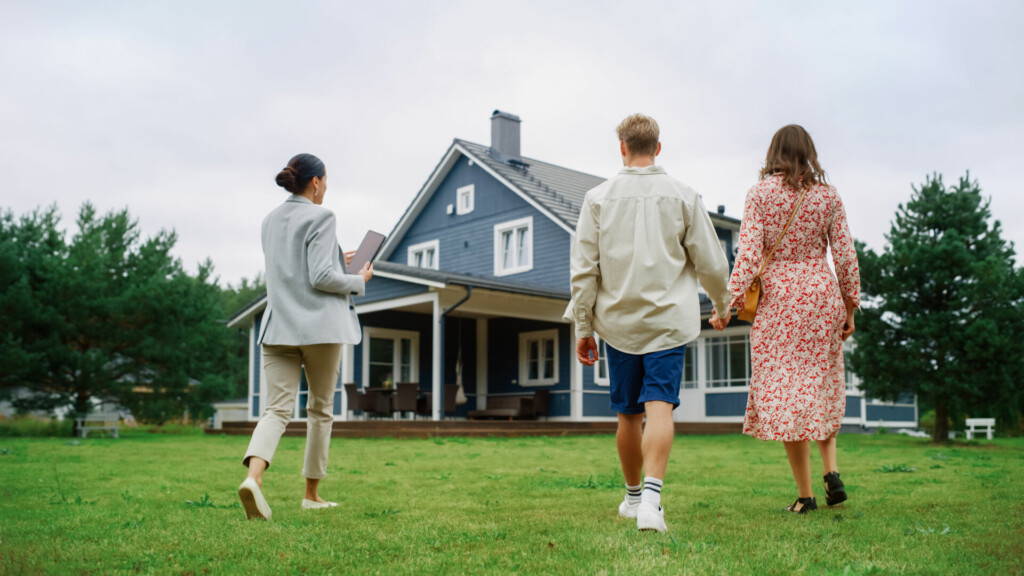 photo : Young Couple Viewing Property for Sale, Talking with Professional Real Estate Agent Outside the House on a Summer Day. Young Beautiful Family are Ready to Become New Homeowners.