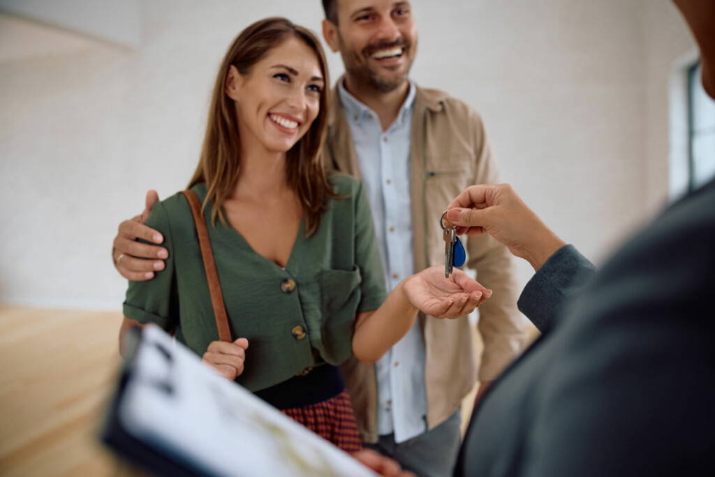 photo : Happy woman and her husband getting keys from real estate agent while buying  new apartment.