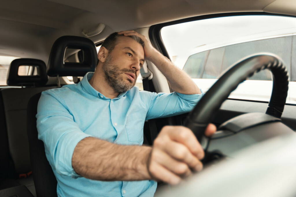 photo : Upset bored man driving new car in city